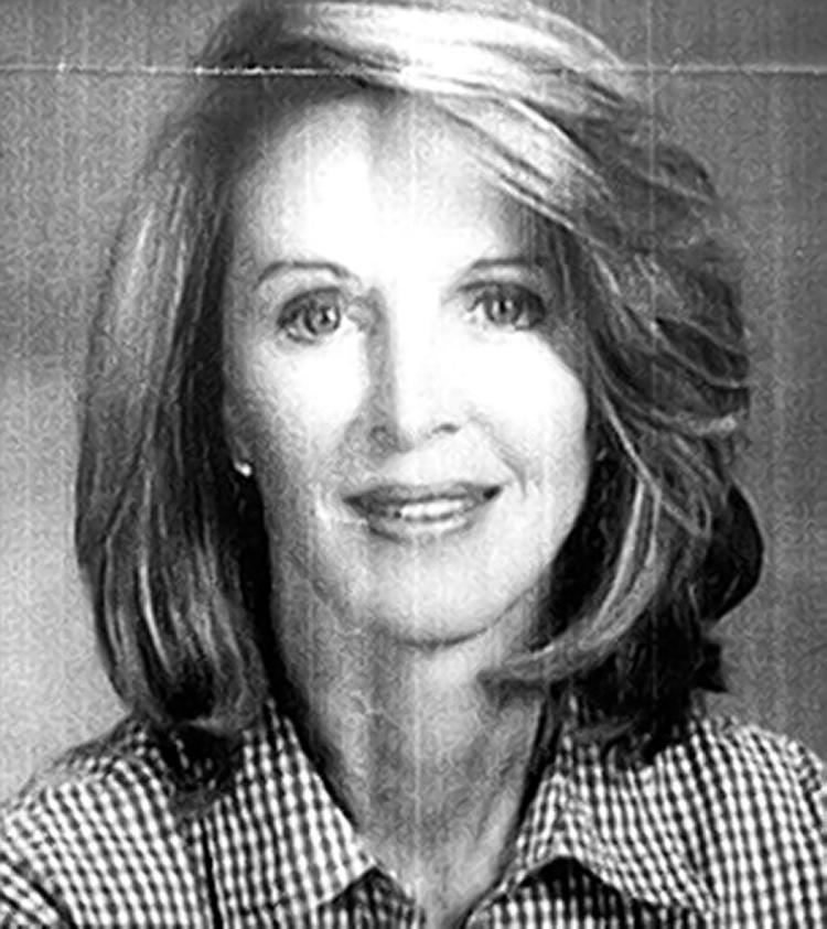 Mary Lynn Witherspoon smiling, with shoulder-length hair and wearing a black and white checkered polo shirt.
