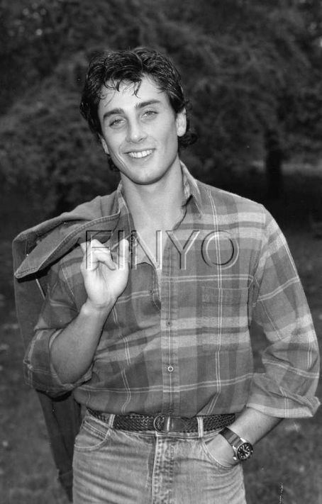 Matt Lattanzi smiling and holding a jacket while wearing checkered long sleeves