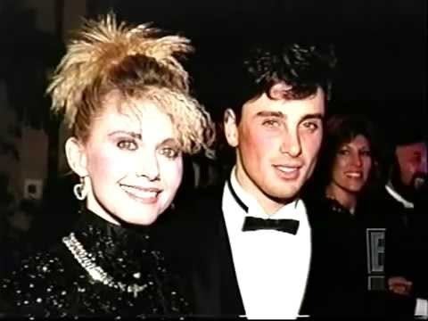 Olivia Newton John smiling and wearing black dress while Matt Lattanzi wearing black coat, white long sleeves and bow tie