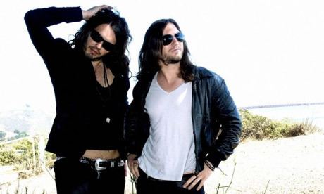 Matt Morgan and Russell Brand wearing black shades, black long sleeves, an inner t-shirt, and black pants