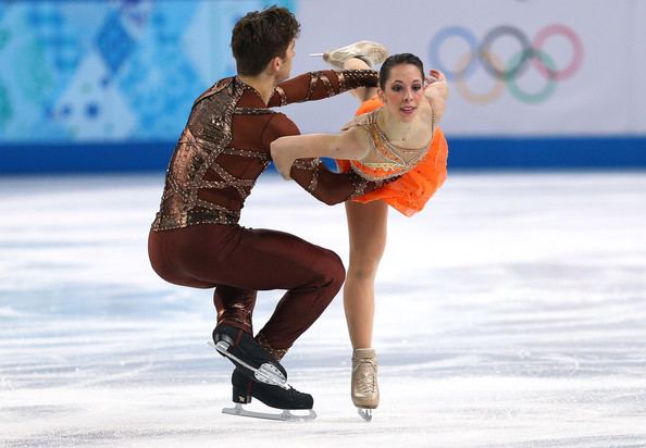 Matteo Guarise and Nicole Della Monica are dancing on the ice during the Figure Skating Pairs Short Program on day four of the Sochi 2014 Winter Olympics at Iceberg Skating Palace on February 11, 2014, in Sochi, Russia. Matteo is wearing brown pants, black skating shoes, brown see-through long sleeves under a brown vest while Nicole is wearing an orange and gold dress and beige skating shoes
