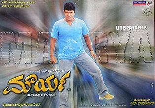The movie poster of Maurya (film) 2004 in a blurry background effect with a written MAURYA at the back, Puneeth Rajkumar is serious standing with his right foot up, has black hair wearing a blue shirt and a gray pants with yellow shoes, at the bottom left is the title written in their language,