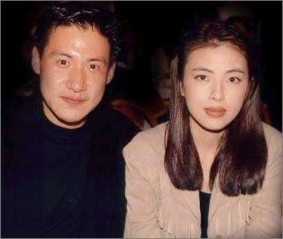 Jacky Cheung smiling and wearing a black shirt while May Lo wearing a brown blazer.