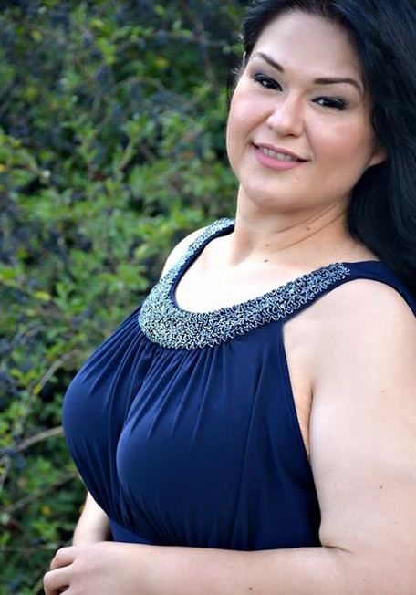 Mayra Rosales posing after losing her obesity with longer hair and wearing a blue sleeveless dress.
