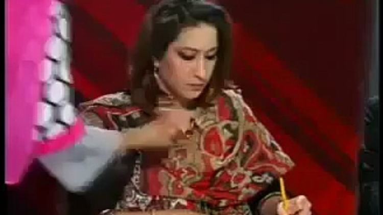 Meher Bukhari writing on the paper while wearing a red and brown blouse