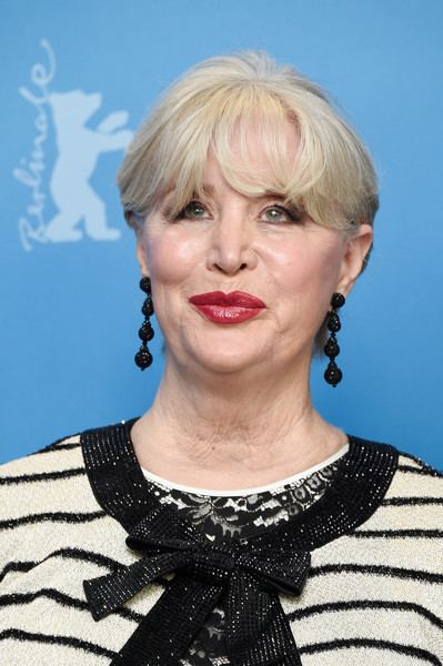 Melinda Ledbetter with short blonde hair, wearing black earrings and a white and black dress.