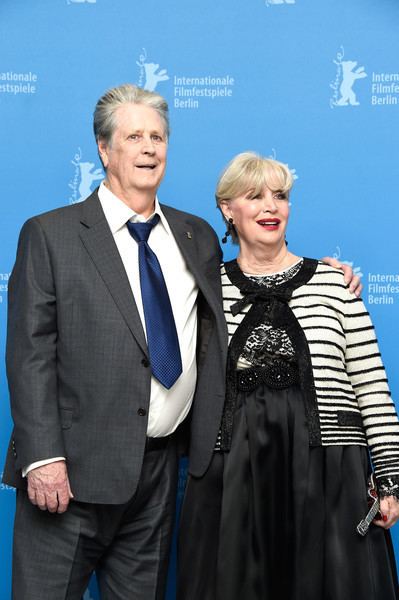 Melinda Ledbetter with short blonde hair, wearing black earrings and a white and black dress with Brian Wilson wearing a suit and a blue tie.