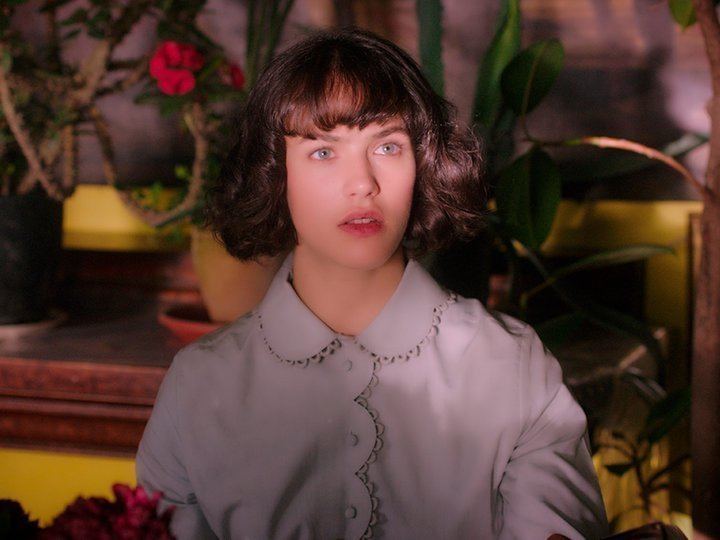 Jessica Brown Findlay looking at something wearing a gray dress in a scene from the 2016 romantic drama film, This Beautiful Fantastic