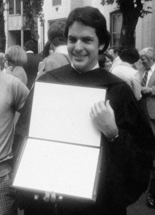 Michael A. Hess during his graduation ceremony while holding his diploma.