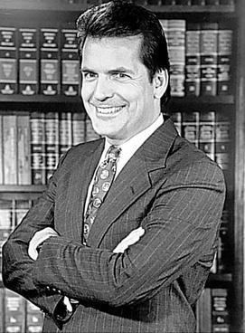 Michael A. Hess wearing a suit and a tie with a lot of books on his back.