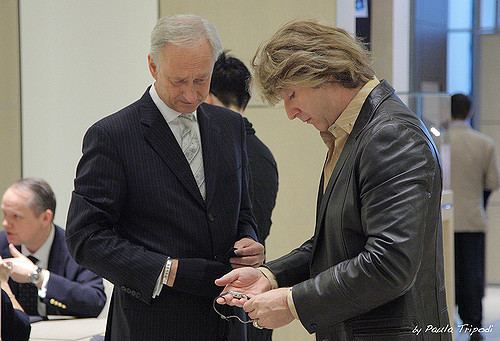 Michael Blakey looking at a watch inside a Mall ang wearing a black leather jacket and a brown collared shirt.