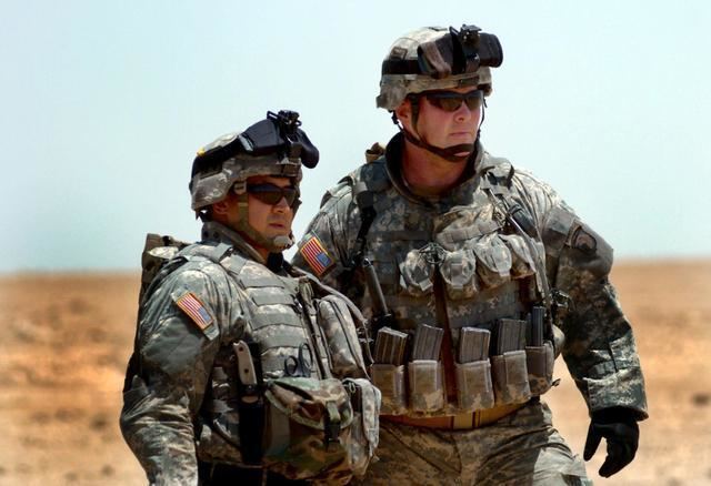 Command Sgt. Maj. Vincent Comacho and Col. Michael Steele looking afar while wearing an army uniform, shades, and helmet