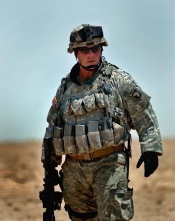 Michael D. Steele holding a gun while wearing an army uniform, shades, and helmet