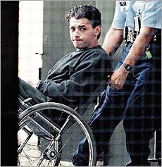 Michael Kanaan in his wheelchair wearing black sweatshirt accompanied by policemen
