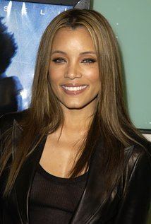 Michael Michele smiling, with long blonde hair and wearing a black jacket.