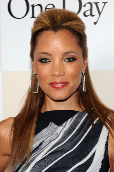 Michael Michele smiling, wearing earrings and a black and white sleeveless top.