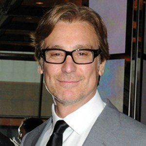 Michael T. Weiss smiling while wearing eyeglasses, gray coat, white long sleeves and black necktie