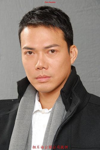 Michael Tse wearing a black jacket, white long sleeves, and gray scarf