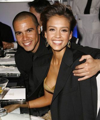 Cash Warren smiling and wearing black long sleeves while Jessica Alba also smiling and wearing a black coat and beige dress