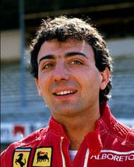 Michele Alboreto smiling while looking afar and wearing a red racing suit