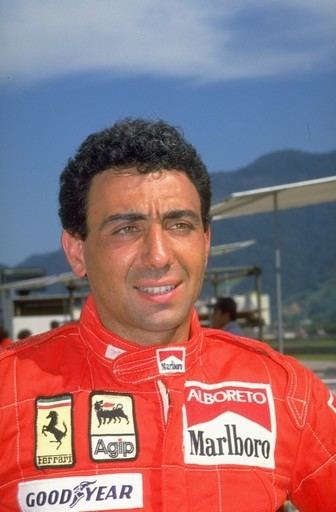 Michele Alboreto smiling while wearing a red racing suit