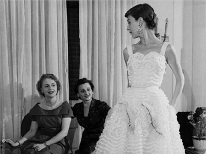 A younger Micol Fontana observing one of her gowns being worn by a model.