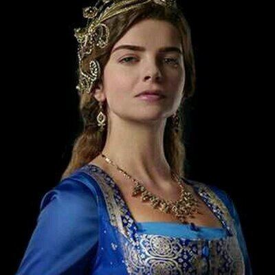 Pelin Karahan as Mihrimah Sultan wearing a blue gown, hair accessory, earrings and necklace in the 2011 tv series, The Magnificent Century