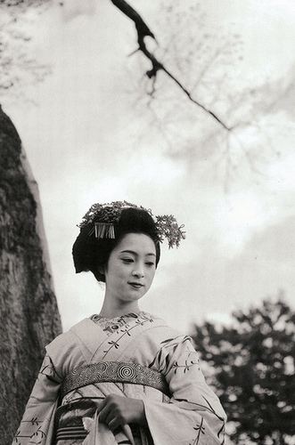 Mineko Iwasaki wearing headdress and kimono while trees on the background