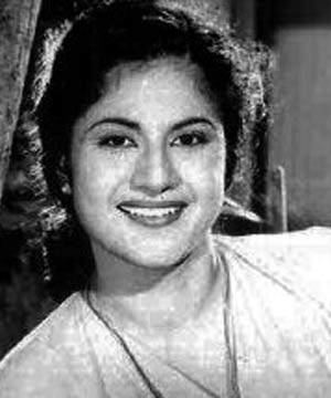 Miss Kumari is smiling, leaning to her right, in black and white, has long black hair, wearing a necklace and white top.