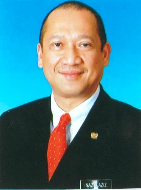 Mohamed Nazri Abdul Aziz posing alone wearing a black coat and a red tie underneath.