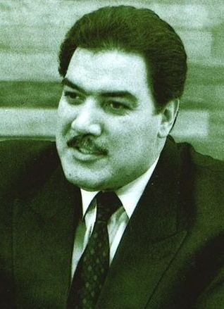 Mohammad Najibullah with mustache while wearing a black coat, white long sleeves, and necktie