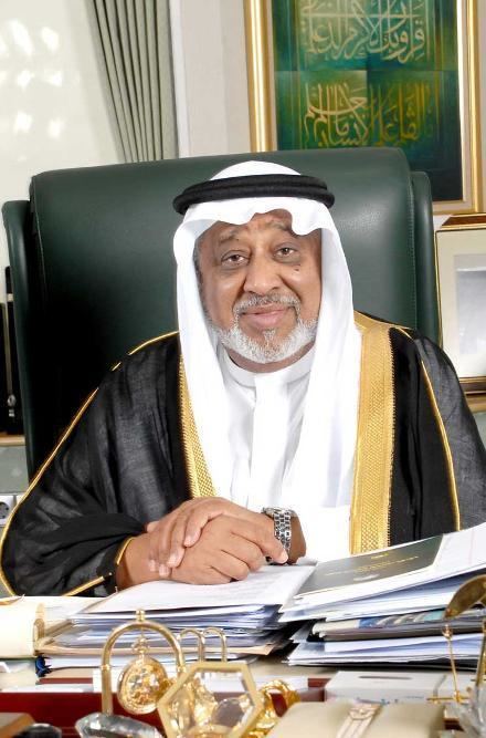Mohammed Hussein Al Amoudi smiling while wearing a black and gold robe, white ghutra and agal