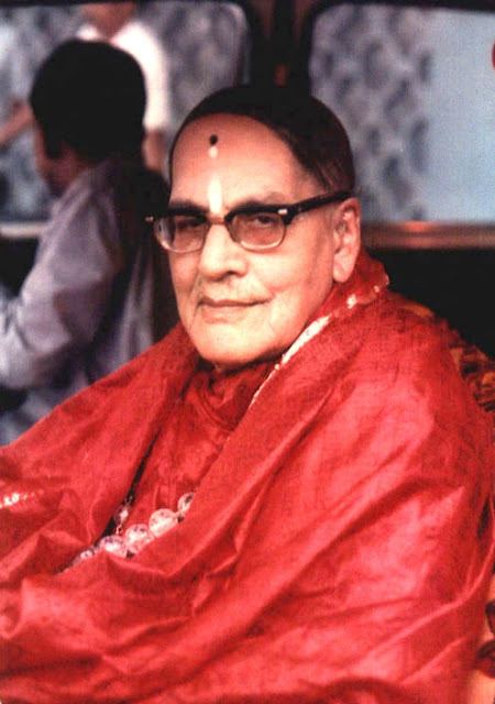 Mohanananda Brahmachari smiling while wearing eyeglasses and red shawl