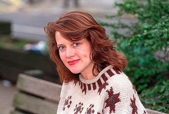 Moira Brooker with blonde hair and a smiling face while wearing a knitted jacket.