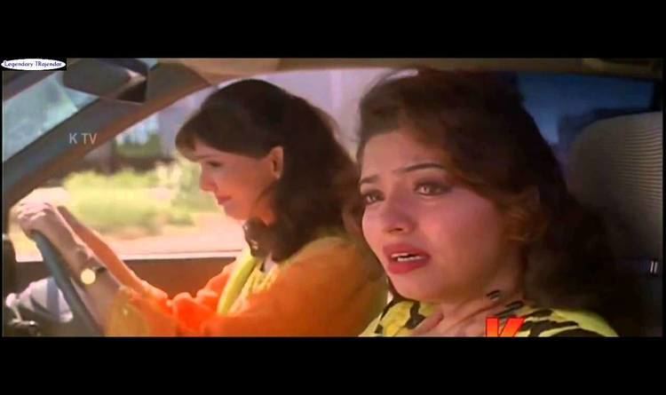 Mumtaj as Monisha inside a car while crying with a woman driving the car and wearing an orange dress in a movie scene from Monisha En Monalisa (1999 film).