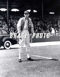 Monty Stratton standing in the middle of the stadium while wearing a jacket, cap, long sleeves, pants, high socks, and shoes