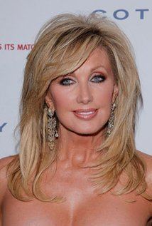Morgan Fairchild smiling and wearing earrings while showing her cleavage