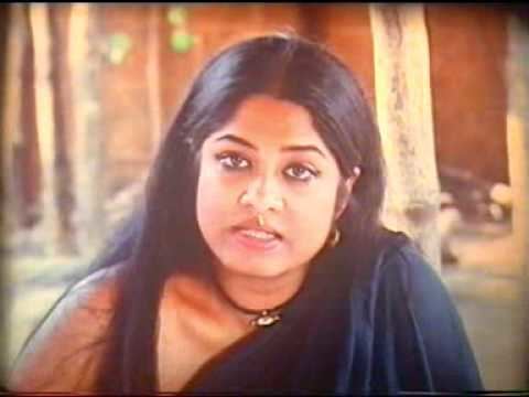 Moushumi wearing a dark blue one-sided sleeve dress, necklace, and earrings in a scene from the Bangla art movie 'Matritto'