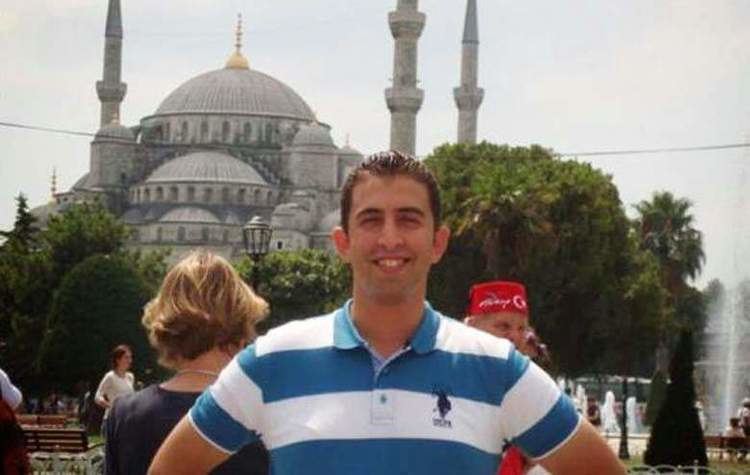 Muath Al-Kasasbeh smiling while wearing a white and blue polo shirt
