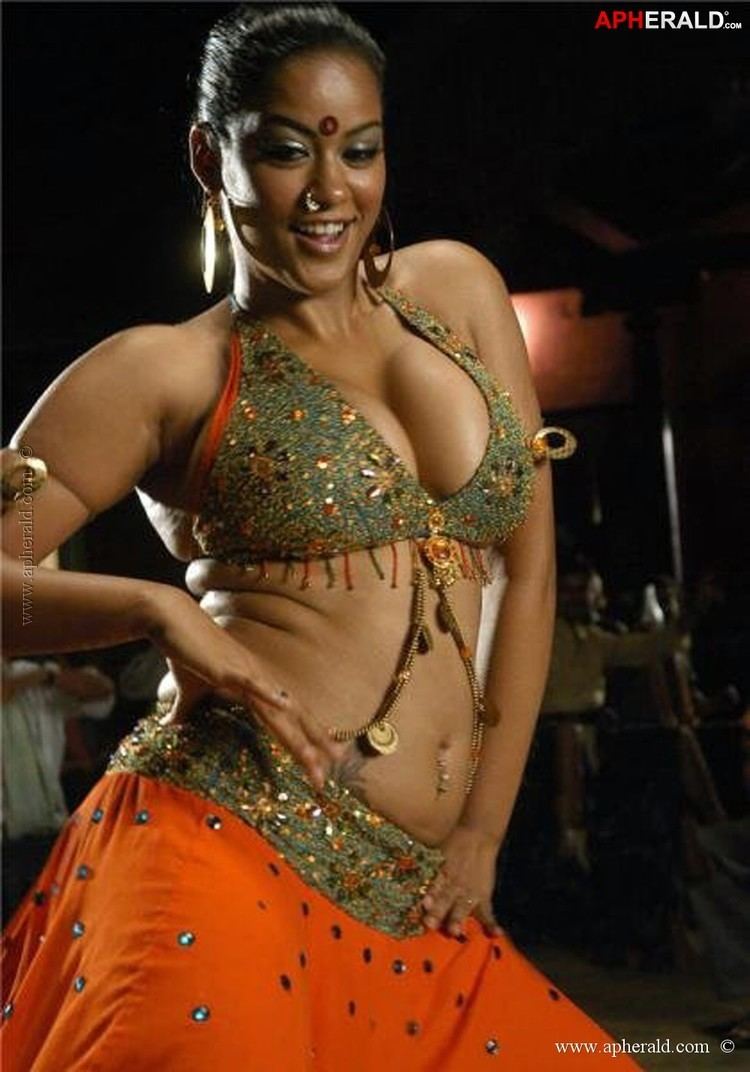 Mumaith Khan smiling while wearing an orange and green belly dancing costume