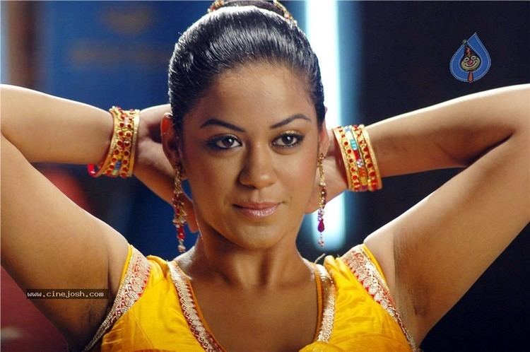 Mumaith Khan smiling while her hands are at the back of her head and wearing a yellow dress and some pieces of jewelry