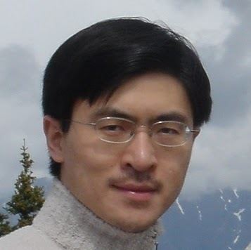 Mung Chiang is smiling, has a short mustache, black straight hair, wearing eyeglasses and a gray sweater.