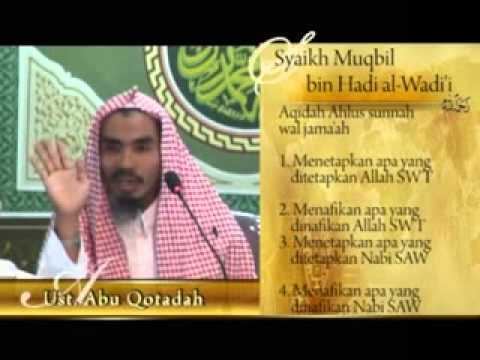 A poster of Muqbil bin Hadi al-Wadi'i wearing hijab while raising his hand with a microphone in front of him.