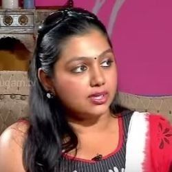 Nandana with a serious face, with sunglasses on her head, wearing earrings, and a red, white, and black Indian dress.