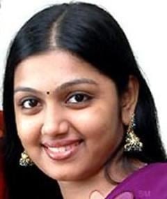 Nandana smiling, with black hair, wearing earrings, and a purple Indian dress.
