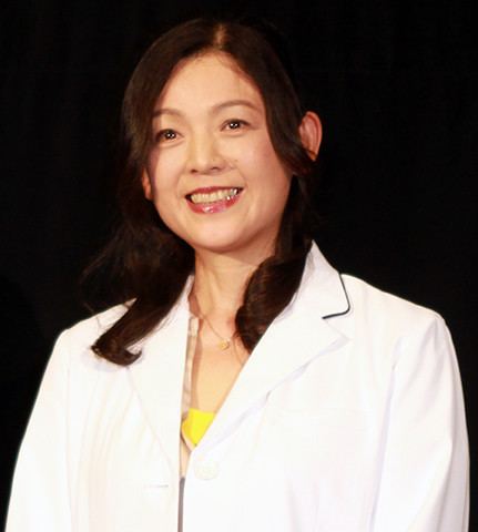 Naomi Morinaga wearing a necklace and a white coat.