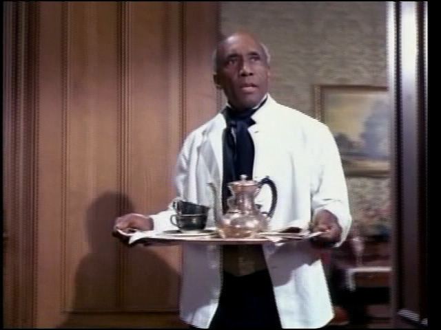 Napoleon Whiting looking afar while holding a serving plate with a kettle and cups