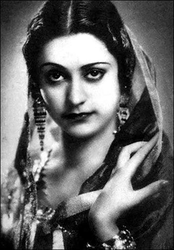 Naseem Banu with a strict face, wearing earrings, bracelets, and a dupatta scarf.