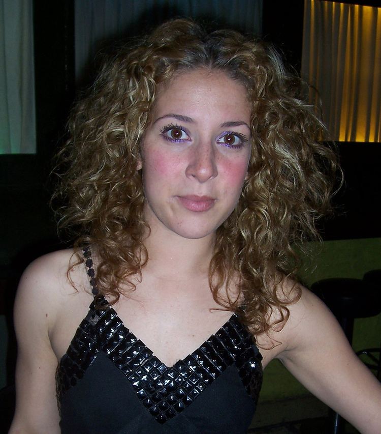 Natalie Casey with curly blonde hair and wearing a black spaghetti top.