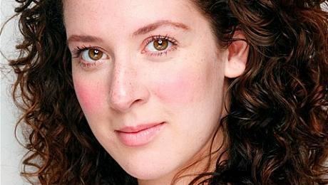 Natalie Casey with a serious face and curly hair.